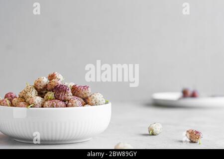 Fresh ripe white mulberries in a ceramic bowl on the table close-up. Selective focus. Space for text Stock Photo