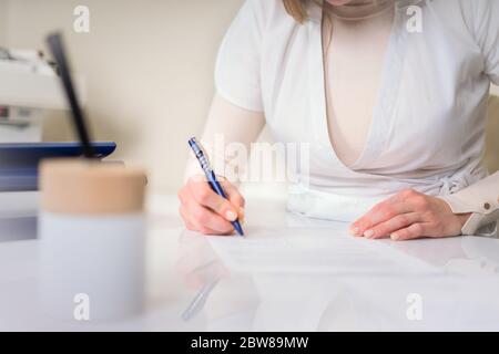 Cropped view of Female young doctor writing something sitting at her office. Healthcare and medical concept Stock Photo