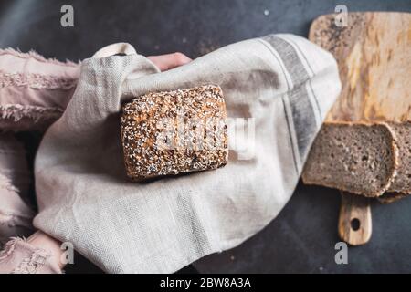Hands holding a multi seed bread and some slices on the background. Stock Photo