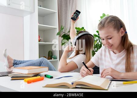 Mother is not helping daughter to do homework while using her smart phone and listening to music with headphones  Stock Photo
