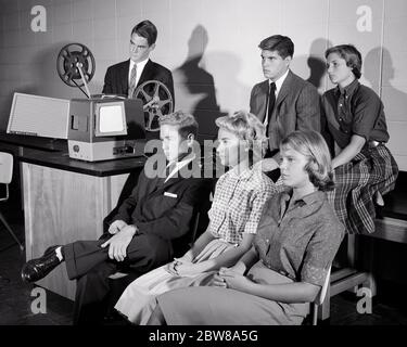 1950s HIGH SCHOOL STUDENTS WATCHING 16MM EDUCATIONAL MOVIE IN CLASSROOM - s10571 HAR001 HARS PERSONS MALES TEENAGE GIRL SIX TEENAGE BOY B&W SKIRTS SCHOOLS SUIT AND TIE PROJECTOR KNOWLEDGE STUNNED EDUCATIONAL HIGH SCHOOL HIGH SCHOOLS AV STYLISH TEENAGED AUDIOVISUAL STONED COOPERATION GROWTH JUVENILES STIFF TOGETHERNESS BLACK AND WHITE BLOUSES CAUCASIAN ETHNICITY HAR001 OLD FASHIONED Stock Photo