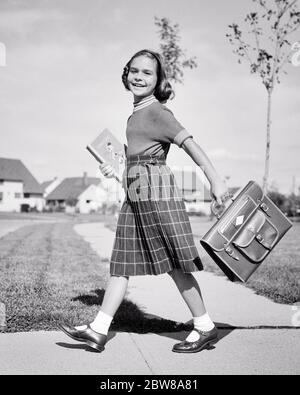 1950s SMILING PRETEEN YOUNG LADY LOOKING AT CAMERA WALKING BRISKLY TO SCHOOL WEARING PLAID SKIRT AND SWEATER CARRYING BOOK BAG  - s2791 DEB001 HARS SWEATER NOSTALGIC BEAUTY SUBURBAN EXPRESSION OLD TIME BUSY NOSTALGIA OLD FASHION 1 JUVENILE FACIAL STYLE COMMUNICATION BLOND BALANCE PLEASED JOY LIFESTYLE SPEED SATISFACTION FEMALES HEALTHINESS HOME LIFE COPY SPACE FULL-LENGTH LADIES PERSONS INSPIRATION TEENAGE GIRL PLAID CONFIDENCE EXPRESSIONS B&W EYE CONTACT GOALS HAPPINESS WELLNESS CHEERFUL ADVENTURE STRENGTH COURAGE AND CHOICE EXCITEMENT KNOWLEDGE LEADERSHIP POWERFUL DIRECTION PRIDE OPPORTUNITY Stock Photo