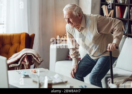 Senior man alone at library trying to stend up leaning on walking stick Stock Photo