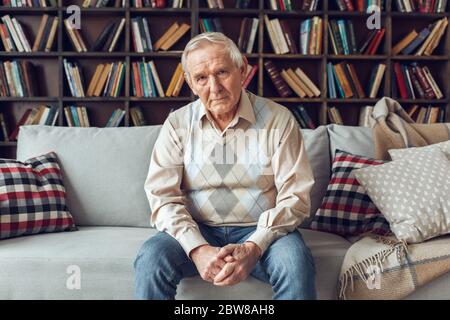 Senior man alone sitting at library looking camera confident Stock Photo