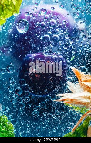 Fresh smoothie with green mint leaves and berries with air bubbles in blue water. close up Stock Photo