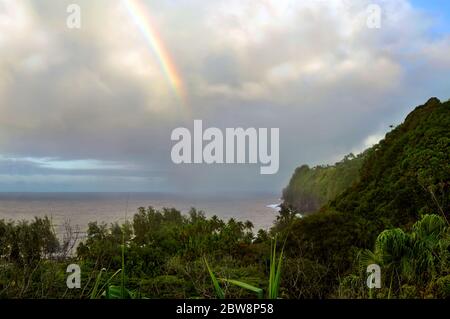 After the rain, a rainbow appears over the Hamakua Coast, at Laupahoehoe Point, on the Big Island of Hawaii.  The showers still fall underneath the cl Stock Photo