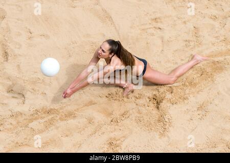Young woman with white ball playing volleyball on beach. Summer vacation and sport concept Stock Photo