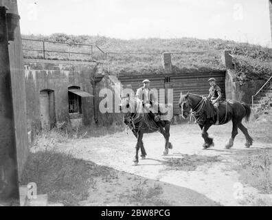 Farm workers ride work horses past an old Fort on Pedham Place farm at Farningham , Swanley, Kent, England . 1935 Stock Photo