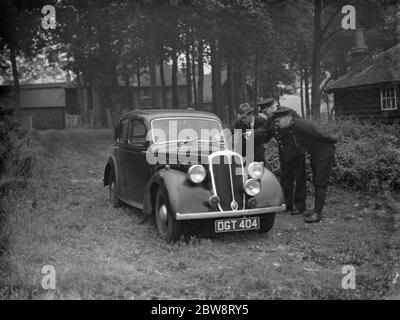 Detectives examine the abandoned getaway car used in the Downe post office robbery . Left to right : Detective Sergeant Trebess of Farnborough police station , P G L Goodliffe , of Bromley police station and P C E Culf of Cudham . 8 September 1938 . Stock Photo