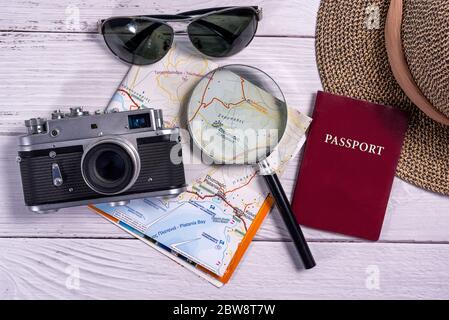 Top view traveler accessories on wooden background. Flat lay vintage camera, sunglasses, map, magnifying glass, straw hat and passport document. Trave Stock Photo