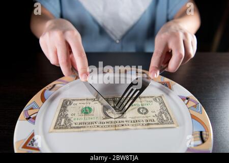 the girl is going to dine with a one dollar bill, which lies on her plate Stock Photo