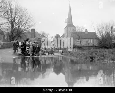 Children paddle in the flooded ford at Eynsford , Kent with St Martin ' s church in the background . 1936 Stock Photo