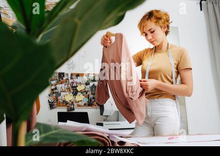 Young tailor girl finishes work on dress  Stock Photo