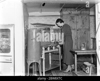 A Bedford truck belonging to Vack Industries Ltd from Kingston upon Thames , London . The truck has been converted into a mobile showroom for their oil burning apparatus. The side of the lorry opens out to reveal the domestic appliances . A woman gives a demonstratin for the cooker . 1937 . Stock Photo