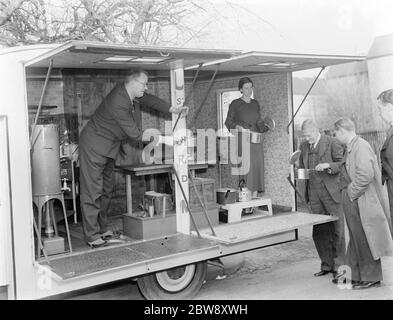 A Bedford truck belonging to Vack Industries Ltd from Kingston upon Thames , London . The truck has been converted into a mobile showroom for their oil burning apparatus. The side of the lorry opens out to reveal the domestic appliances . A man and a woman give a demonstration . 1937 . Stock Photo