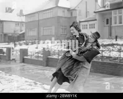 Miss Muriel Oxford is carried over the snow by a young man . 1937 Stock Photo