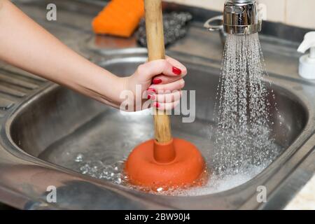 woman cleans plunger with clogged sink, close up Stock Photo