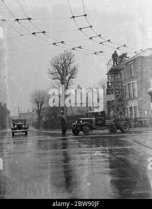 Workers from the Demolition and Construction Company Ltd use their Bedford Tram Tower truck to work on the overhead electrical trolleybus wires . 1937 . Stock Photo