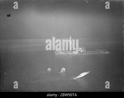 A small boat hovers at the side of the plane crash . The Royal Air Force Avro 621 Tutor K6090 is upside down in the Dartford Creek showing only its undercarriage and a wing tip . 31 January 1939 Stock Photo