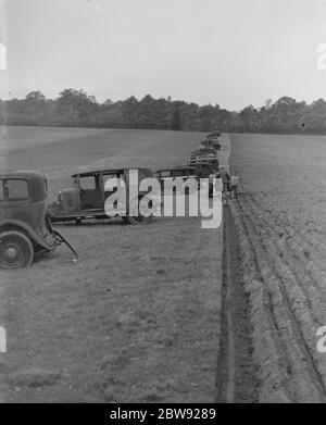 A farmer ploughing a field with a tractor . Alongside are old cars which have been parked in order to cause obstruction to enemy gliders carrying invasion troops which may want to land on the field . 1939 . Stock Photo