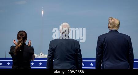 In this photo released by the National Aeronautics and Space Administration (NASA), President Donald Trump, right, Vice President Mike Pence, and Second Lady Karen Pence watch the launch of a SpaceX Falcon 9 rocket carrying the company's Crew Dragon spacecraft on NASA's SpaceX Demo-2 mission with NASA astronauts Robert Behnken and Douglas Hurley onboard, Saturday, May 30, 2020, from the balcony of Operations Support Building II at NASA's Kennedy Space Center in Florida. NASA's SpaceX Demo-2 mission is the first launch with astronauts of the SpaceX Crew Dragon spacecraft and Falcon 9 rocket to Stock Photo