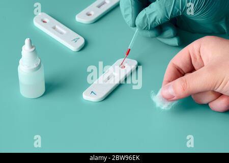 Express COVID-19 test for IgM and IgG antibodies to novel coronavirus SARS-CoV-2, Covid-19. Nurse hand in glove applies blood to the test with pipette Stock Photo