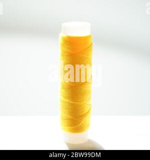 Yellow thread spool on a white bright table, side view Stock Photo