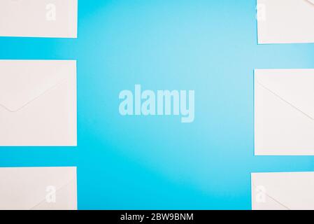 Blue background with white paper envelopes with empty space in the center. Stock Photo