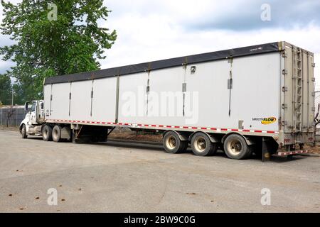A big rig semi-trailer truck parked idle on the side of a road. Stock Photo