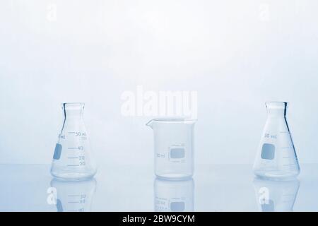 clear glass beaker and flask in clean white blue research and develoment science laboratory background