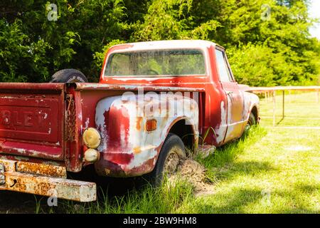 Abandoned Antique red truck parked in a field on a farm Stock Photo