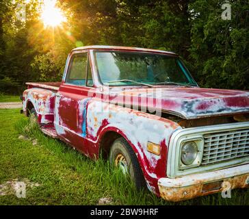 Antique red truck parked in a field on a farm Stock Photo