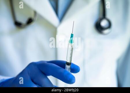 Close-up of gloved doctors hand holding syringe Stock Photo