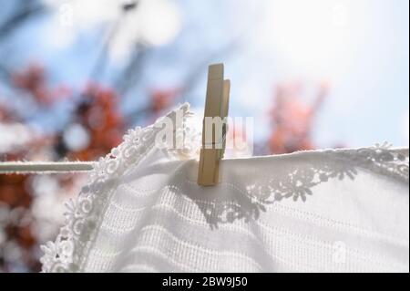 White tablecloth drying on clothesline in sunlight Stock Photo