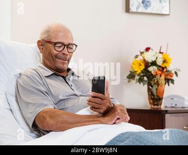 Senior man lying in bed and using smart phone Stock Photo