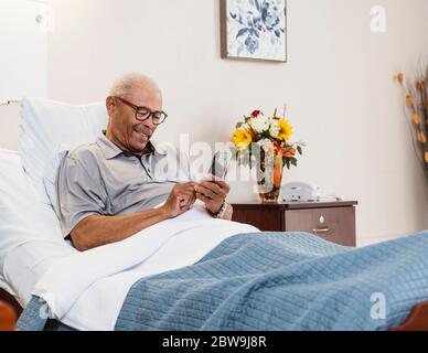 Senior man lying in bed and using smart phone Stock Photo