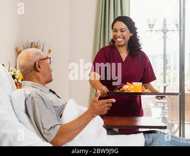 Nurse bringing healthy meal to senior man in bed Stock Photo