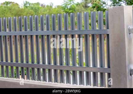 fence wall made of gray metal and white bricks on a rural street Stock Photo