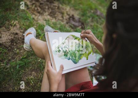Switzerland, Obergoms, Young woman painting withÂ watercolorÂ in Swiss Alps Stock Photo