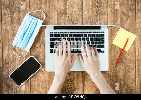 Working from home on a computer during COVID pandemic. Female person using laptop in the home office. Stock Photo