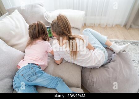 Two sisters Lying On Couch And Using Tablet, top view Stock Photo