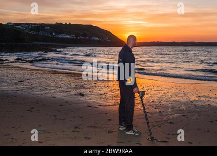 Myrtleville, Cork, Ireland. 31st May, 2020. An early morning riser pauses for a minute to watch the sunrise as searches for lost items at the beach in Myrtleville, Co.Cork, Ireland. Weather today on the South coast are bright and sunny with tempertures of 22 - 26 degrees celcius. - Credit; David Creedon / Alamy Live News Stock Photo