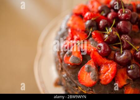 Traditional homemade chocolate cake sweet pastry dessert with brown icing, cherries, raspberry, currant on vintage wooden background. Dark food photo Stock Photo