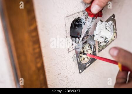 Closeup of electrician hands fixing a socket. Stock Photo