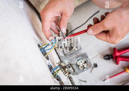 Closeup of electrician hands fixing a socket. Stock Photo