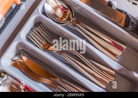Opened kitchen drawer with a tray and cutlery inside. Grey front of the drawer, white inside Stock Photo