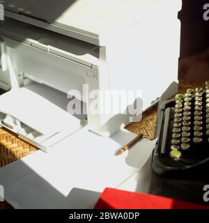 Retro typewriter and a modern printer placed on a table Stock Photo