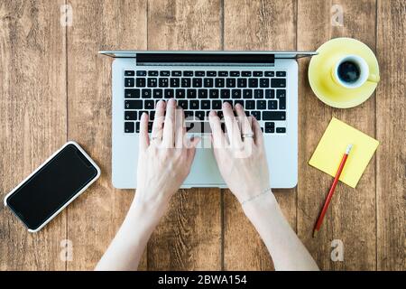 Computer laptop usage for creative remote home office work. Young woman using keyboard and smartphone for modern digital enabled corporation. Stock Photo