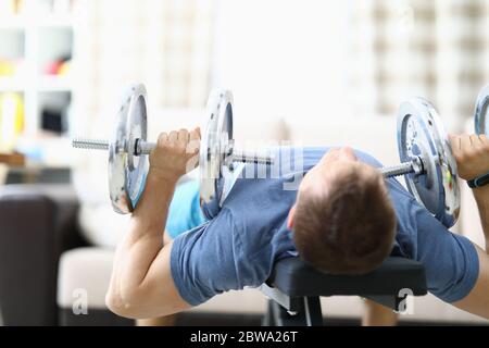 Man doing strength exercises with dumbbells home Stock Photo