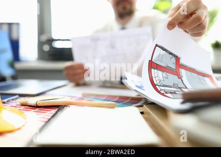 Male designer sits at table and looks floor plan Stock Photo